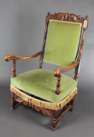 A 17th Century style carved walnut open arm chair with cresting rail carved Prince of Wales feathers, raised on turned and block supports with carved apron, the seat and back upholstered in green Dralon (frame loose) 