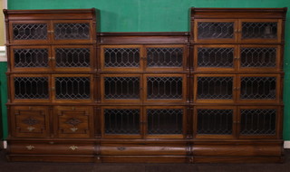A suite of Globe Wernicke style mahogany bookcases in 3 sections, all with moulded cornice and Grecian key decoration, the first section fitted 3 stepped and graduated bookcases enclosed by lead glazed panelled doors above 2 filing drawers with drawer to base, the second and centre section with raised back fitted 3 stepped bookcases enclosed by lead glazed panelled doors and having drawer to base, the third section fitted 4 stepped and graduated bookcases and fitted a drawer.   The measurements of the first and third section are 60"h x 36"w x 12"d, the middle section is 50 1/2"h x 36"w x 12"d 
