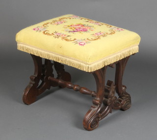 A Victorian carved mahogany Gothic style stool, the seat upholstered in Berlin woolwork, raised on pierced supports with turned stretcher 16"h x 19 1/2" x 16"w 