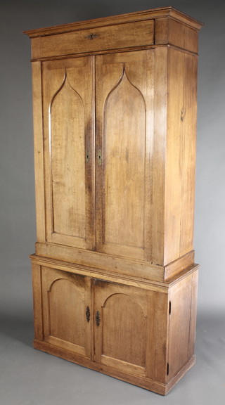 A 19th Century Dutch oak cabinet on cabinet, the upper section fitted a drawer above a pair of cupboards enclosed by arch panelled doors, the base fitted a cupboard 86"h x 41"w x 17 1/2"d 
