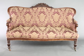 An early Victorian carved mahogany show frame sofa, the carved cresting rail decorated flower heads and upholstered in red and floral patterned material, the seat of serpentine outline, raised on turned and reeded supports 40 1/2"h x 63"w x 34"d 
