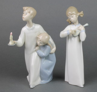 A Lladro figure of a girl playing a mandolin 8" and a Lladro group of a young boy and girl with chamber stick 8 1/2" 