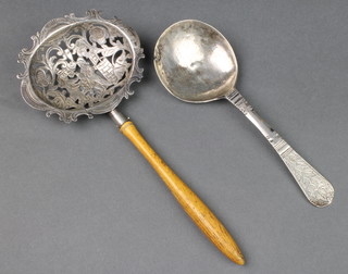 A Continental pierced silver sifter spoon with wooden handle, decorated with figures before a well, import marks London 1884, an 18th Century Continental silver spoon with floral decoration 