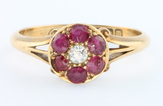 An 18ct yellow gold ruby and diamond cluster ring the centre brilliant cut diamond surrounded by 6 rubies size P 