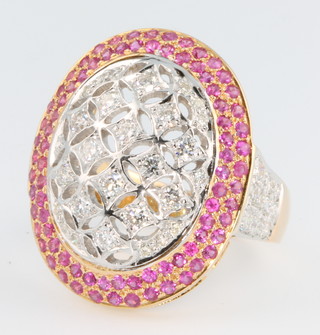A yellow gold ruby and diamond cocktail ring, the pierced centre panel of diamonds surrounded by 2 tiers of rubies, the shank with diamond set shoulders, rubies approx 0.9ct, diamonds approx 1.27ct, size O, with certificate 