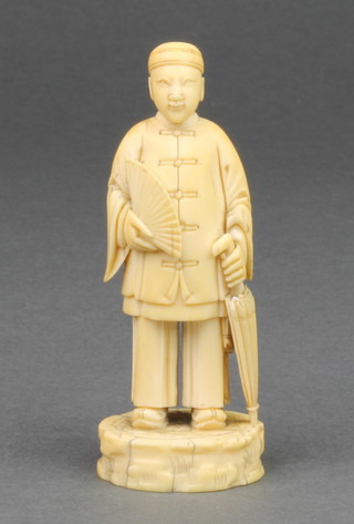A 19th Century carved Chinese figure of a standing Chinaman holding a fan and an umbrella 3 1/2" 