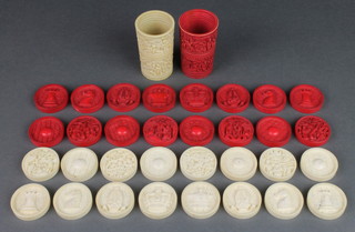 A set of 32 carved and stained Cantonese ivory draughts or backgammon counters depicting figures in garden landscapes and chess symbols together with 2 shakers