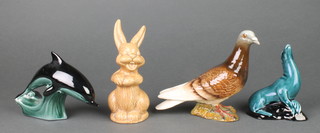 A Beswick figure of a seated pigeon, incised 1385 6", a Poole Pottery figure of a dolphin 5", ditto sea lion 5" and a Sylvac style figure of a rabbit 6" 