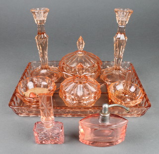 An Art Deco 7 piece pressed amber tinted glass dressing table set comprising tray, pair of candlesticks, 2 circular jars and covers, circular jar and a ring tree together with a pink tinted glass boat shaped perfume atomiser 2" (chips to base) and pink glass scent bottle 4" 