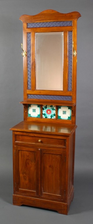 A Victorian style mahogany hall stand, the upper section with shaped top fitted a bevelled plate mirrored panel, the base fitted a shelf above a tiled back and having 1 long drawer above a cupboard enclosed by panelled doors 78"h x 24"w x 12 1/2"d 