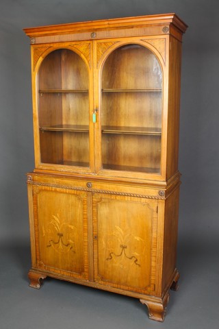 A Victorian inlaid walnut cabinet on cabinet, the upper section with moulded cornice, fitted shelves enclosed by arched panelled doors, the base fitted a cupboard enclosed by inlaid panelled doors, raised on ogee bracket feet 68 1/2"h x 37"w x 16"d 