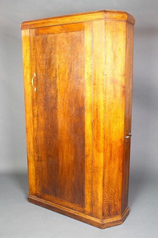A 1930's Art Deco oak lozenge shaped hall wardrobe with moulded cornice and carrying handles to the sides, enclosed by panelled doors and raised on a platform base 67"h x 41"w x 12"d 