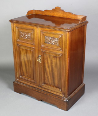A Waring & Gillow Victorian carved walnut cabinet, the top with three-quarter gallery enclosed by panelled doors, raised on a platform base 37"h x 28"w x 16"d 