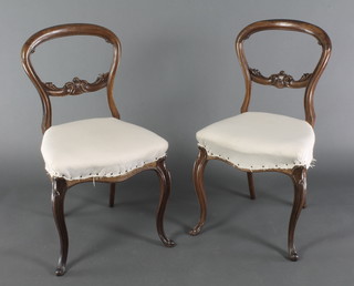 A pair of Victorian rosewood balloon back dining chairs with carved mid rails, the seats of serpentine outline 