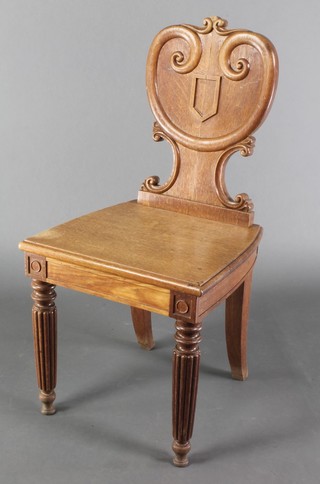 A Victorian oak hall chair with shield shaped back and solid seat, raised on turned and reeded supports 