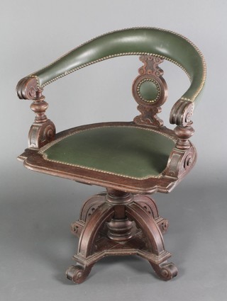 A Pugin style oak tub back revolving chair raised on a bulbous and X framed base 