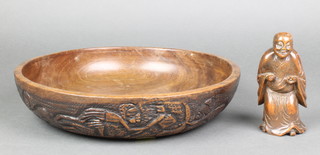 A circular carved African hardwood bowl decorated figures 12" and a Chinese carved hardwood figure of a standing Deity 5" 