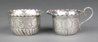 A Victorian silver repousse cream jug and sugar bowl with scroll decoration and cast armorial Sheffield 1887, 100 grams