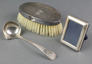 A silver hair brush, a ditto photo frame and a Georgian silver ladle 