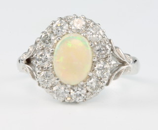 An 18ct white gold opal and diamond cluster ring, the centre stone approx 1.25ct surrounded by 11 diamonds, size M 