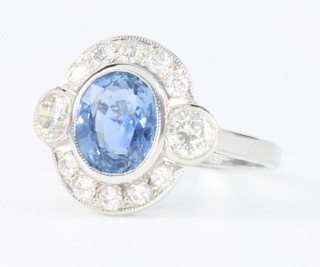 An 18ct white gold oval sapphire and diamond cluster ring, the centre stone approx. 2ct surrounded by 10 brilliant cut diamonds and 1 diamond to each shoulder, size N 1/2