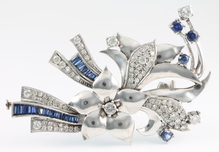 A white gold diamond and sapphire floral spray brooch comprising 33 tapered baguette cut sapphires and 4 brilliant cut sapphires together with 77 brilliant cut diamonds, 24 grams, 3" x 2" 