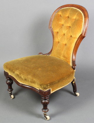 A Victorian mahogany show frame nursing chair upholstered in gold buttoned dralon, the seat of serpentine outline, raised on turned supports 