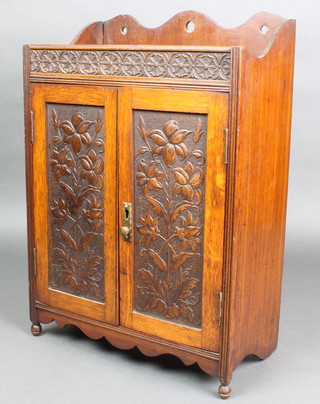 An Edwardian Art Nouveau carved oak hanging smokers cabinet with raised back, enclosed by panelled doors 18"h x 12 1/2"w x 7"d 