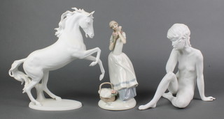 A Kaiser bisque figure of a stallion 10", a ditto of a seated naked lady 9" and a Continental figure of a standing girl 10" 