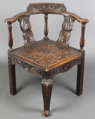 A Georgian oak corner chair with slatted back, raised on cabriole and square legs all heavily carved throughout 

