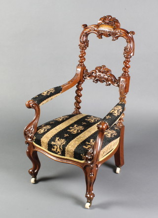 A childs Victorian carved mahogany open arm chair, upholstered in blue and cream striped material, the cresting rail carved October 12 and the middle rail carved 1861, raised on cabriole supports


