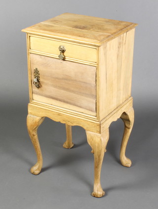 A bleached oak bedside cabinet fitted a drawer above cupboard, raised on cabriole supports 29"h x 16"w x 14"d 