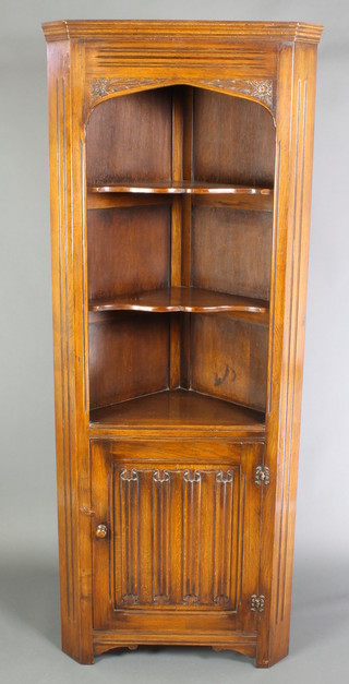 An "Ipswich" style oak corner cabinet, the upper section with moulded cornice and arched aperture, fitted 2 shelves, the base enclosed by a linenfold panelled door 71"h x 28"w x 15 1/2"d 