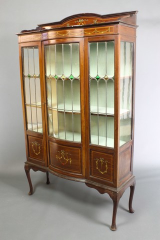 An Edwardian Art Nouveau inlaid mahogany bow front display cabinet, the raised back with three-quarter gallery, fitted shelves enclosed by lead glazed panelled doors, painted garland panels throughout,  raised on cabriole supports 70"h x 42"w x 13"d 