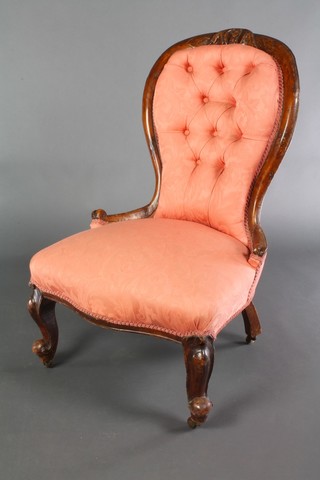 A Victorian carved walnut show frame nursing chair upholstered in pink buttoned material raised on cabriole supports