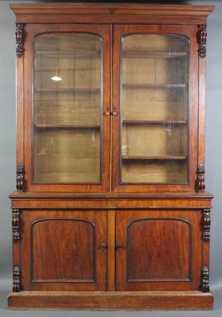 A Victorian mahogany bookcase on cabinet, the upper section with moulded cornice, fitted adjustable shelves enclosed by arched panelled doors having vitruvian scrolls to the sides, the base fitted a cupboard enclosed by panelled doors, raised on a platform base 102"h x 83"w x 20"d 
