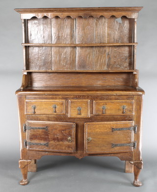A 17th Century style oak dresser of small proportions, the raised back with shaped and moulded cornice fitted 2 shelves, the base fitted 1 short drawer flanked by 2 long drawers with brass pear drop handles above a cupboard enclosed by panelled doors, raised on club supports 64"h x 46"w x 17"d 