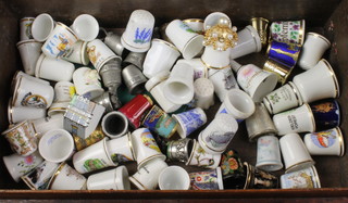 A collection of mainly porcelain collectors thimbles, contained in a wooden box