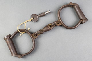 A pair of iron handcuffs marked Hiatt Best Warranted Rought 30 complete with keys