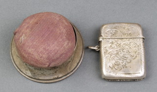 A circular silver pin cushion 2 1/2" and a chased vesta 