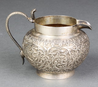 A repousse Indian silver jug with scroll decoration and cobra handle