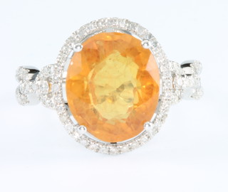 A 14ct white gold yellow sapphire and diamond open cluster ring, the centre stone approx. 5.75ct and approx. 0.65cts of diamonds, size M 1/2
