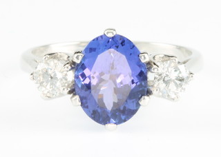 An 18ct white gold tanzanite and diamond ring, the center oval stone approx. 3ct flanked by 2 diamonds approx. 0.5ct size O 1/2