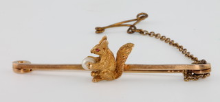 An Edwardian 15ct yellow gold squirrel bar brooch with ruby eye, holding a cultured pearl