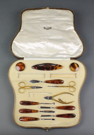 An Edwardian fitted leather case containing 12 etched (ex 14) piece faux tortoiseshell manicure set  