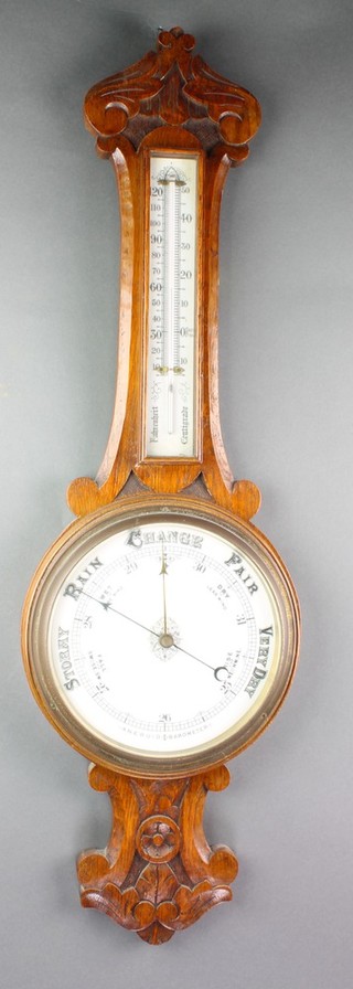 An aneroid barometer and thermometer with enamelled dial contained in a carved oak case 