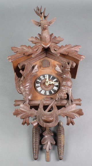 A cuckoo clock contained in a carved wooden case surmounted by a stag, the sides decorated game