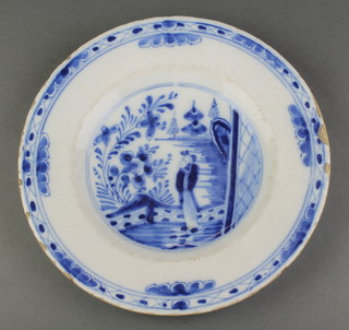 An 18th Century English Delft plate decorated with a figure in a garden landscape within a geometric border 9 1/2" 