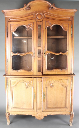 A 19th Century French pine cabinet on cabinet, the upper section with shaped cornice, the base fitted a cupboard enclosed by glazed panelled doors, the base fitted a cupboard enclosed by panelled doors, raised on cabriole supports 95"h x 55 1/2"w x 19"d 