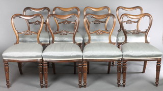 A set of 8 Victorian rosewood buckle back dining chairs with shaped mid rails and over stuffed seats, raised on turned and fluted supports 